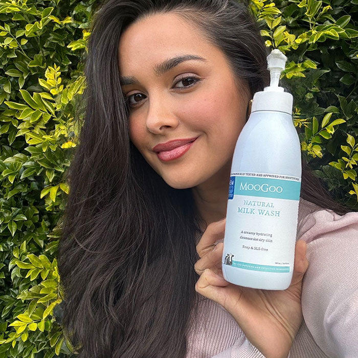 Woman smiling while holding MooGoo Natural Milk Wash, gentle hydrating cleanser for sensitive face and body
