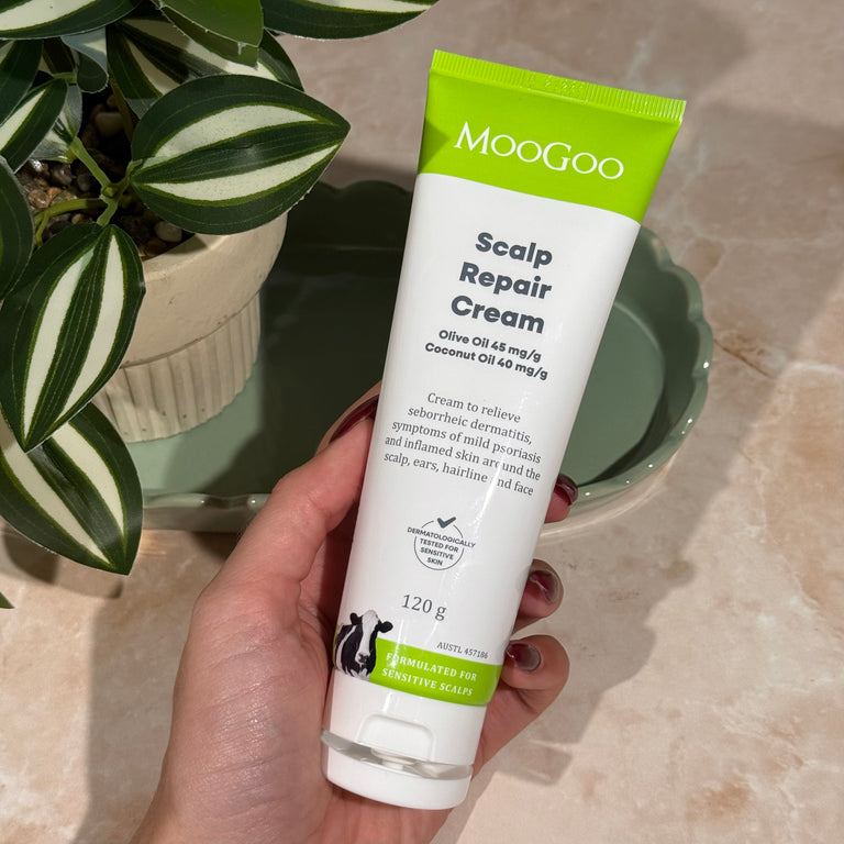 Hand holding MooGoo Scalp Repair Cream tube, natural cream for seborrheic dermatitis and psoriasis