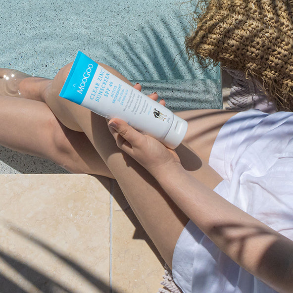 Woman holding MooGoo Clear Zinc Sunscreen SPF 40, natural zinc oxide sunscreen for sensitive skin with broad spectrum UVA UVB protection