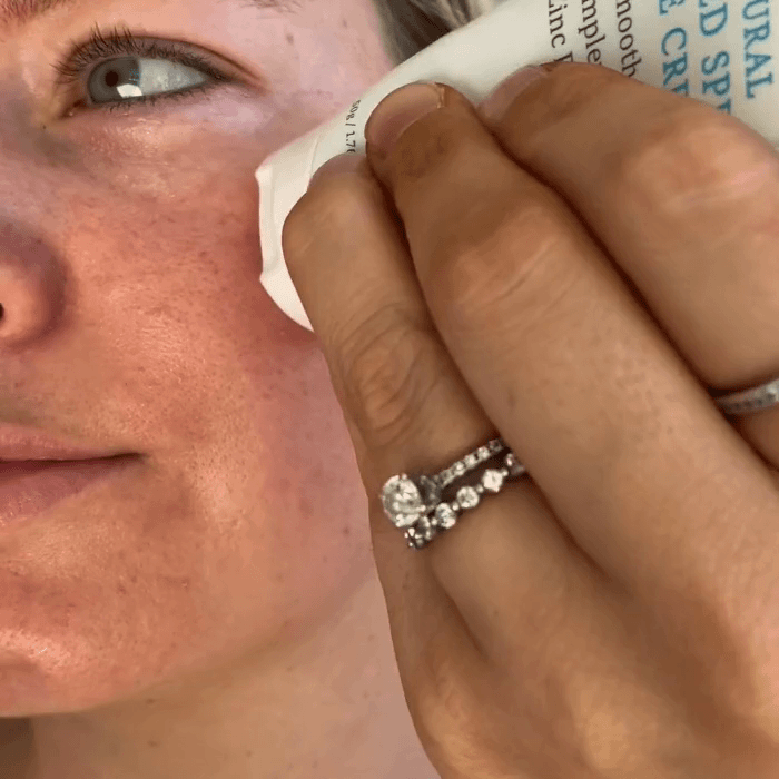 Woman applying MooGoo Tinted SPF 40 Face Cream, a zinc SPF 40 tinted formula for natural glow, protection from UVA UVB, non-greasy finish.