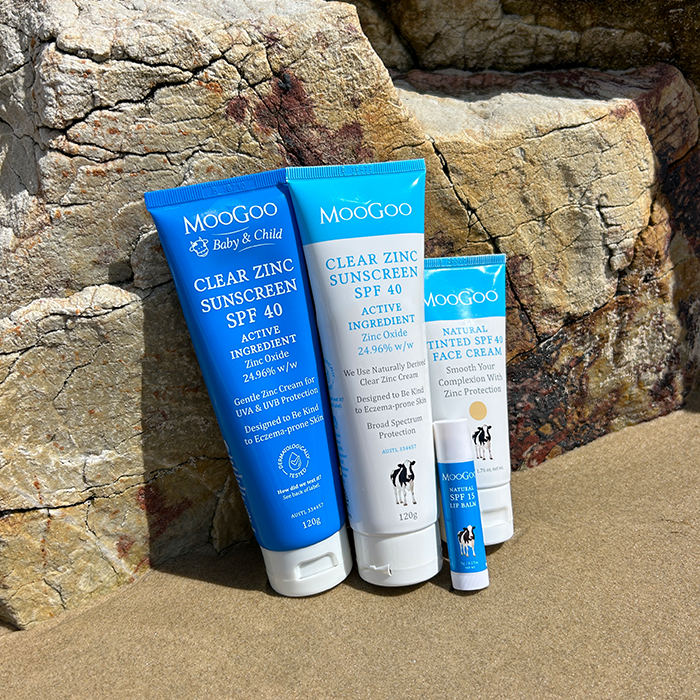 MooGoo Clear Zinc Sunscreen SPF 40 leaning on rock with Baby Range Sunscreen, Tinted SPF40 Face Cream, and SPF15 Lip balm, with broad spectrum protection, water resistant, gentle on sensitive and eczema-prone skin.
