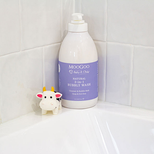 MooGoo natural 2 in 1 bubbly wash with white tile background, Cow toy next to bottle. Hypoallergenic and SLS free to soothe sensitive skin