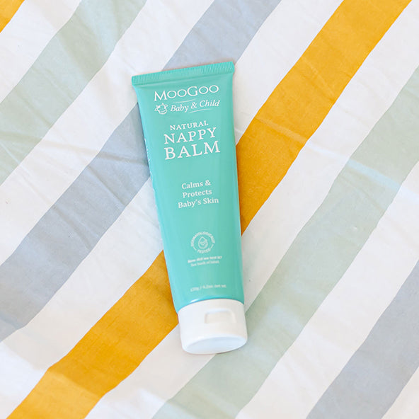 MooGoo Baby & Child Natural Nappy Balm on striped fabric background, zinc-based barrier cream to calm and protect baby skin from nappy rash irritation