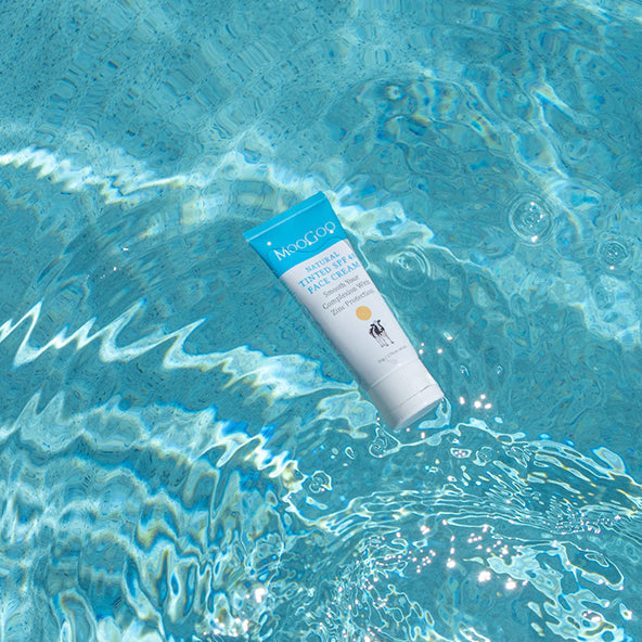 MooGoo Tinted SPF 40 Face Cream on pool surface, zinc SPF 40 face sunscreen with tint to balance skin tone, reduce redness, defend against UV rays.