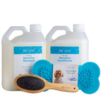 Dr. Zoo Natural Sensitive Shampoo and Sensitive Conditioner kit for dogs, featuring two large white plastic bottles, two bright blue lick-and-stay mats, and a wooden grooming brush with black bristles, all on a white background.