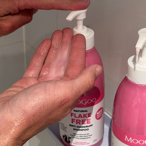MooGoo natural Pink Flake Free Shampoo against shower background, gentle SLS-free shampoo to fight dandruff and soothe itchy, flaky scalp