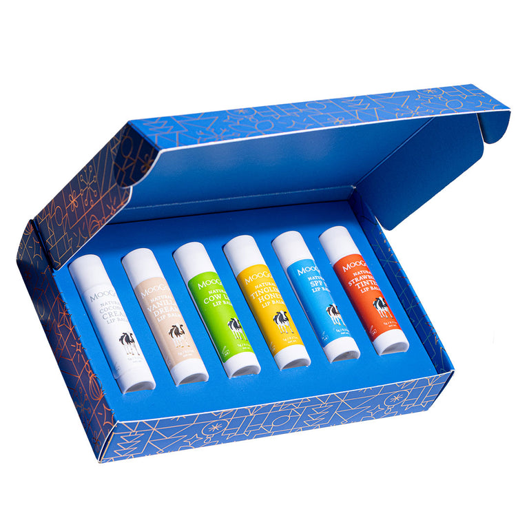 MooGoo Natural Lip Balm Christmas Gift Set in blue themed packaging on a white background, with the box open, displaying six MooGoo Lip Balm flavours in various colours.