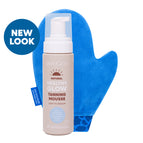 MooGoo Healthy Glow Tanning Mousse bottle in a light beige shade, shown with a bright blue microfiber mitt behind it on a white background. Lightweight water foam self tanner with aloe vera and pro vitamin B5. 