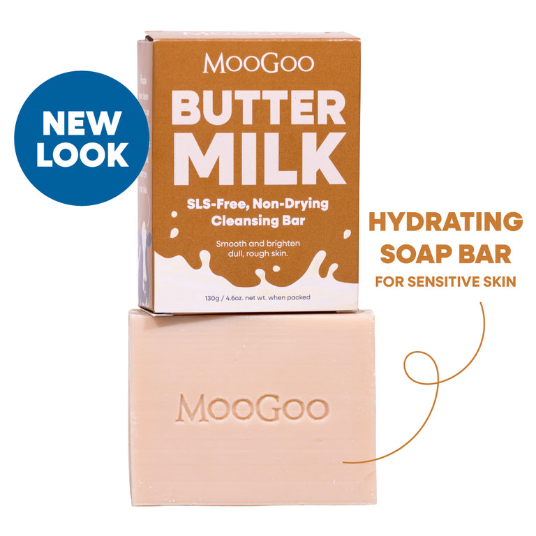 MooGoo Butter Milk SLS-Free Non-Drying Cleansing Bar shown with its brown cardboard box and the pale peach soap bar stacked below. A blue circular 'NEW LOOK' badge appears on the left, and text on the right reads 'HYDRATING SOAP BAR FOR SENSITIVE SKIN'. For dry skin, natural oils, SLS free and gentle on sensitive skin. 