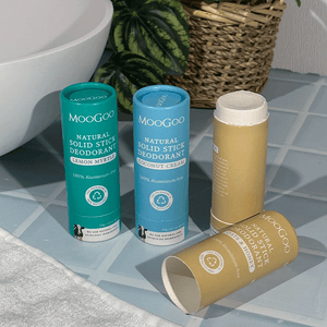 MooGoo 65g Natural Solid Stick Deodorants displayed on a bathroom counter with a plant partially in the background. 100% aluminium free, plastic-free natural odour control.