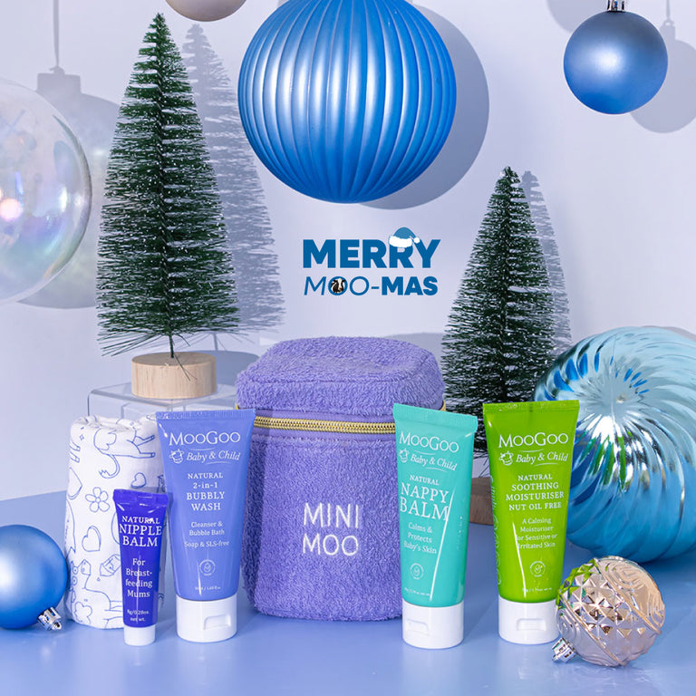 MooGoo Baby Travel Pack on a Christmas-themed background, newborn travel essentials bundle with 2-in-1 bubbly wash, Natural Nappy Balm, Natural Nut Oil Free Soothing Moisturiser, Nipple Balm and Baby Cloth.