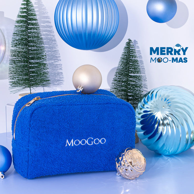 Blue MooGoo Terry Towelling Cosmetics Travel Bag with a gold zipper on a Christmas-themed background.