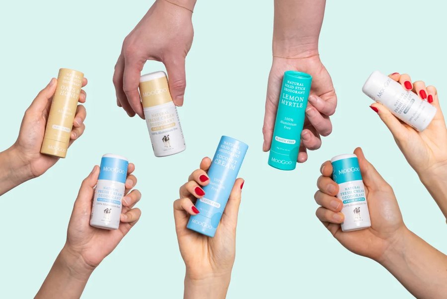 Hands holding the full MooGoo roll-on and stick natural deodorant range