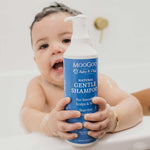 baby in bath with shampoo foam on scalp and holding MooGoo Gentle Shampoo, natural tear-free formula for delicate newborn and child skin